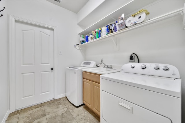 laundry area with visible vents, baseboards, washing machine and dryer, cabinet space, and a sink