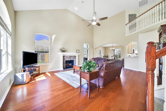 living area with visible vents, arched walkways, wood finished floors, and a tile fireplace