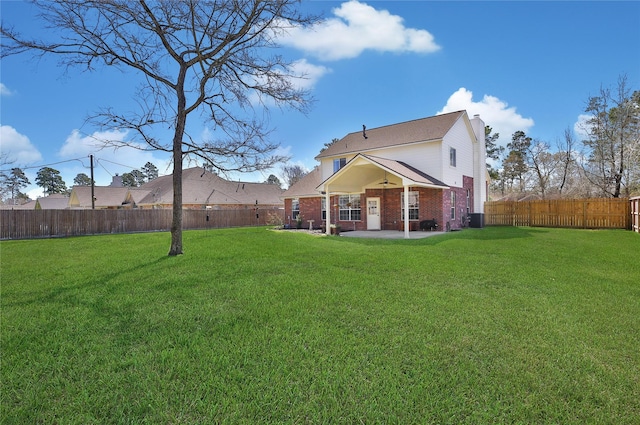 rear view of house with brick siding, a fenced backyard, a patio, and a yard