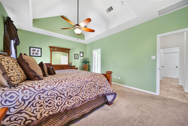 carpeted bedroom with a ceiling fan, a tray ceiling, baseboards, and visible vents