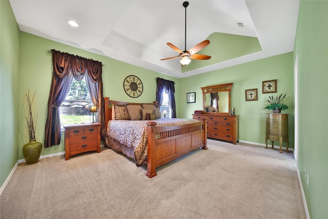 carpeted bedroom with visible vents, baseboards, a tray ceiling, recessed lighting, and a ceiling fan