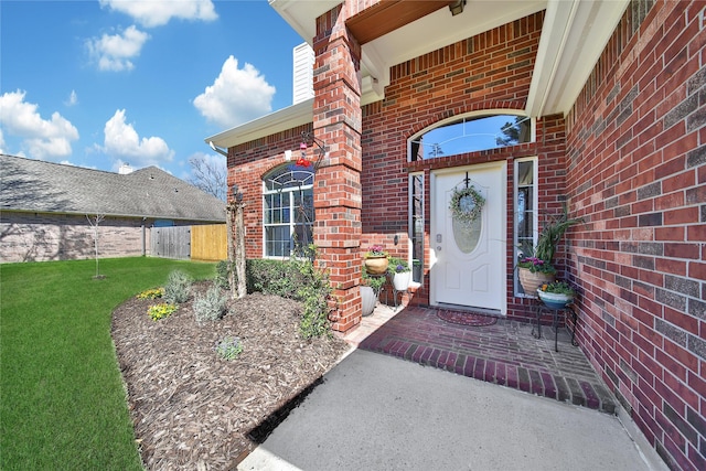 doorway to property featuring brick siding and fence