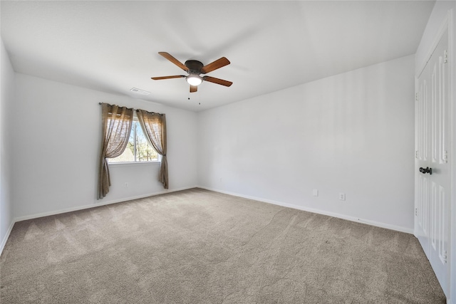 carpeted spare room featuring visible vents, baseboards, and ceiling fan