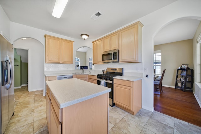 kitchen featuring visible vents, light brown cabinets, stainless steel appliances, arched walkways, and light countertops