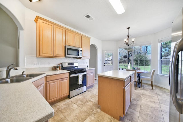 kitchen featuring visible vents, a kitchen island, a sink, appliances with stainless steel finishes, and tasteful backsplash