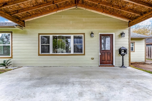 doorway to property featuring a patio and a shingled roof