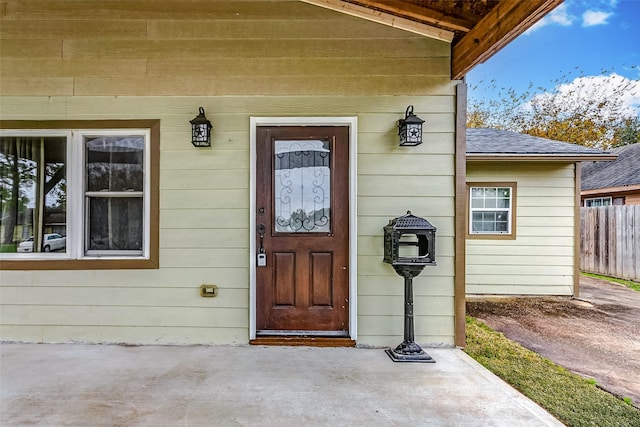 doorway to property with fence and roof with shingles