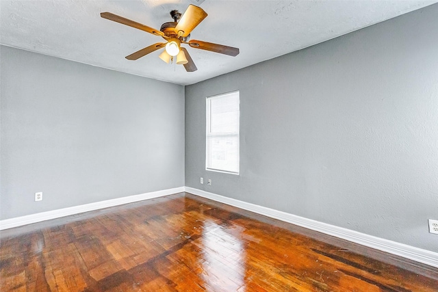 unfurnished room with dark wood finished floors, ceiling fan, and baseboards