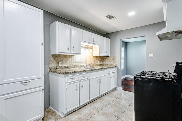 kitchen with visible vents, backsplash, gas stove, white cabinetry, and a sink