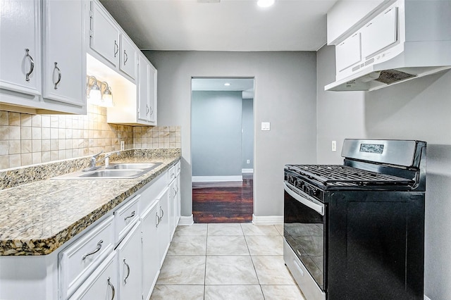 kitchen with a sink, backsplash, white cabinets, light tile patterned floors, and stainless steel range with gas stovetop