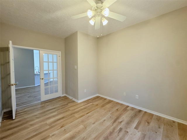 empty room with light wood-style flooring, a ceiling fan, baseboards, and a textured ceiling