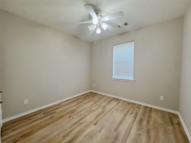 empty room with a ceiling fan, visible vents, light wood finished floors, and a textured ceiling