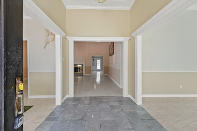 foyer with tile patterned floors, a glass covered fireplace, baseboards, and ornamental molding