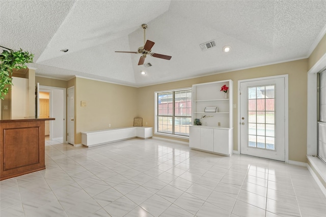 empty room with visible vents, a healthy amount of sunlight, crown molding, and vaulted ceiling