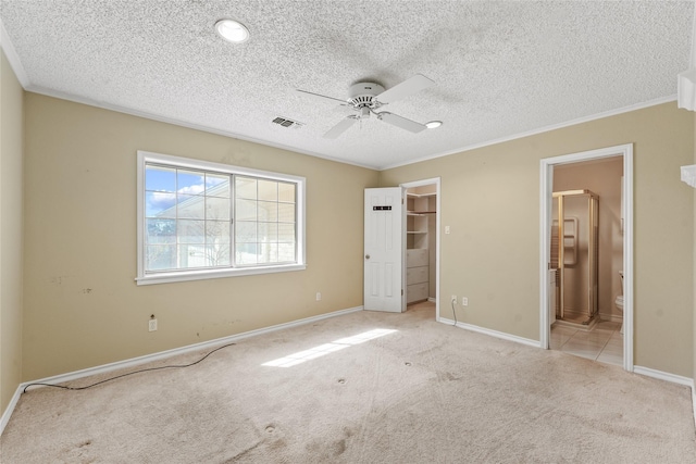 unfurnished bedroom with baseboards, a walk in closet, carpet, and ornamental molding