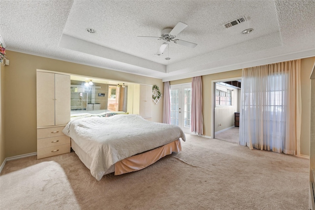 bedroom with visible vents, a raised ceiling, and access to exterior