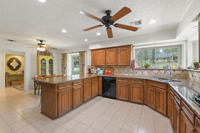 kitchen with brown cabinets, black dishwasher, visible vents, and a sink