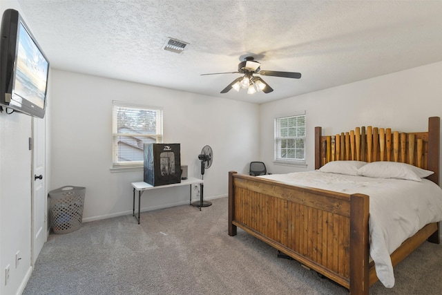 carpeted bedroom featuring baseboards, visible vents, a textured ceiling, and ceiling fan