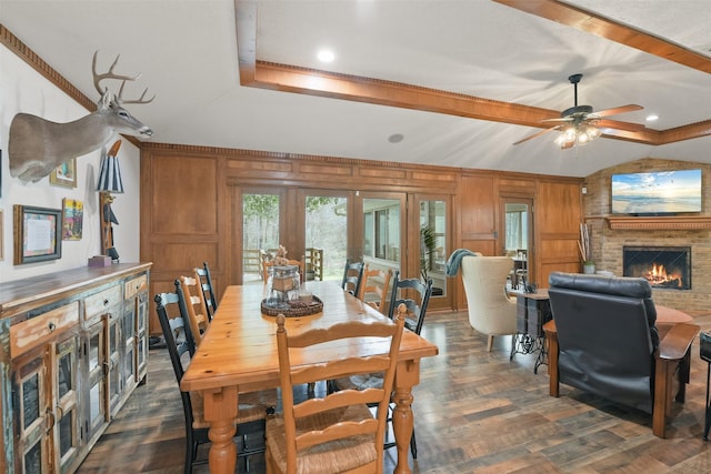 dining room with wood walls, a fireplace, dark wood-type flooring, and ceiling fan