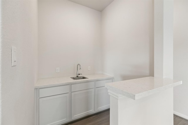bar area featuring a sink, dark wood finished floors, and baseboards