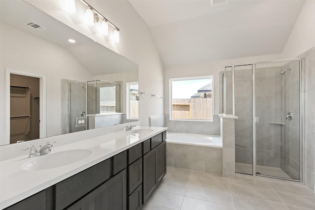 full bathroom featuring vaulted ceiling, a shower stall, tile patterned floors, a bath, and a walk in closet