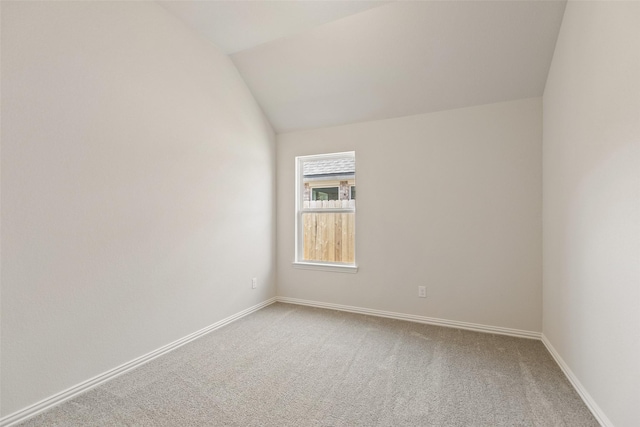 unfurnished room featuring carpet flooring, lofted ceiling, and baseboards