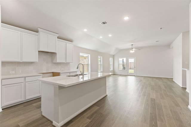 kitchen with a sink, a center island with sink, ceiling fan, white cabinetry, and light wood-style floors