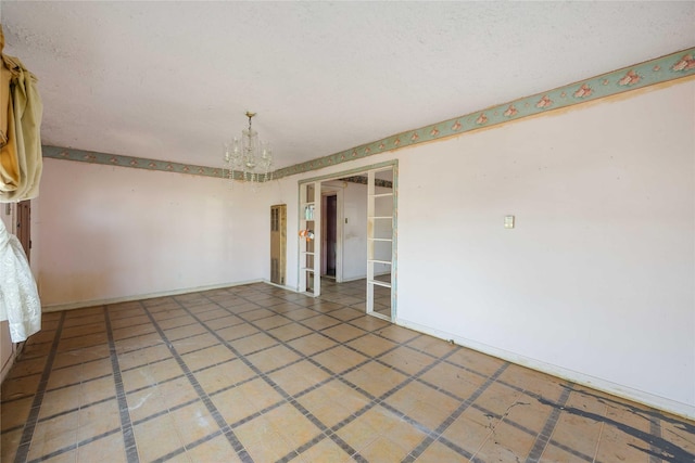spare room featuring baseboards, a textured ceiling, and a chandelier
