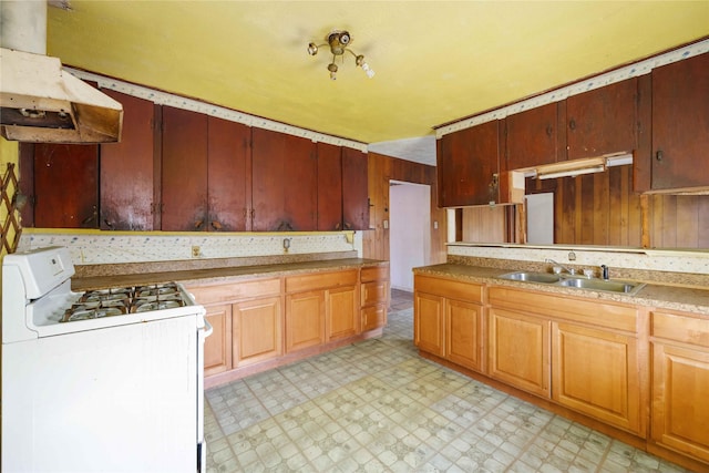 kitchen with white range with gas cooktop, a sink, under cabinet range hood, light countertops, and light floors