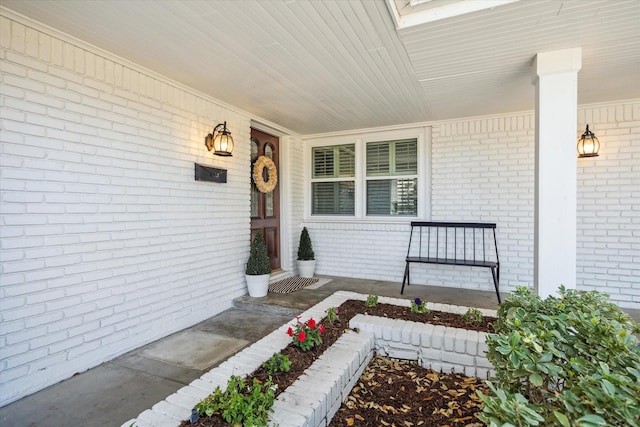 doorway to property featuring brick siding and covered porch