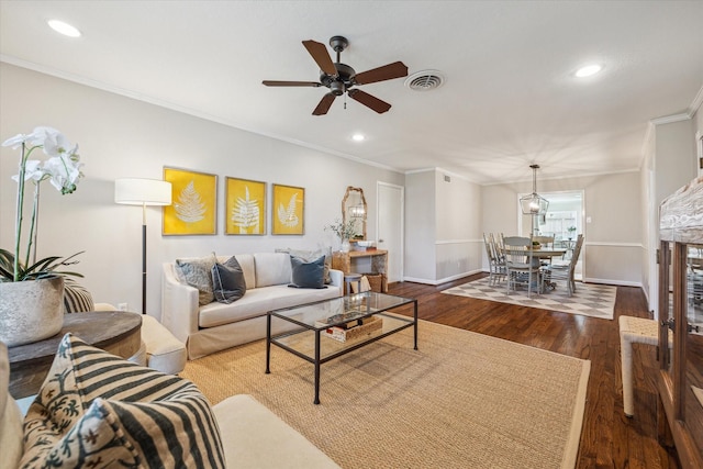 living room featuring visible vents, ornamental molding, baseboards, and wood finished floors