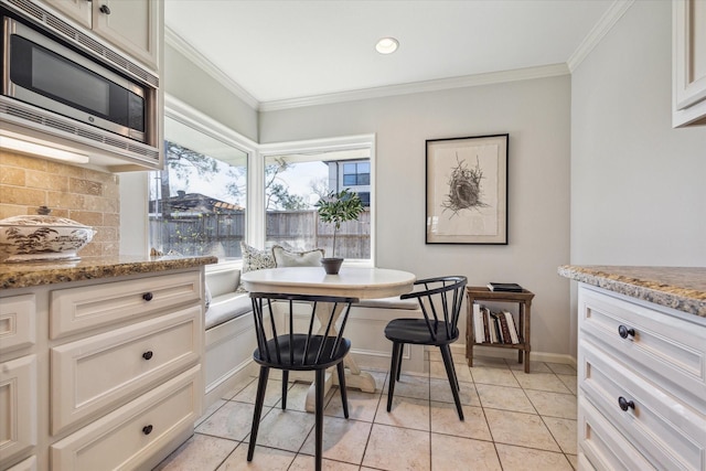 dining area featuring breakfast area, baseboards, ornamental molding, and light tile patterned flooring