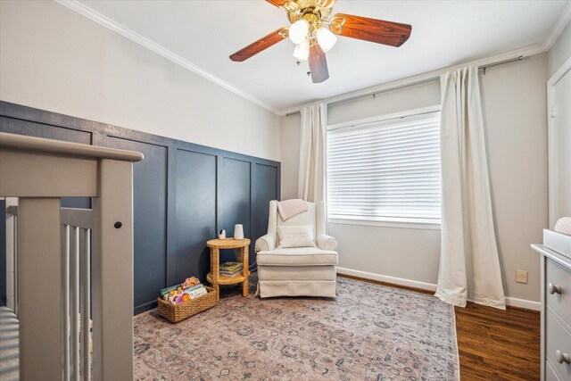 sitting room featuring ceiling fan, baseboards, wood finished floors, and crown molding