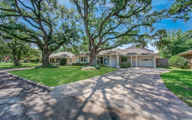 ranch-style house with a front yard, fence, a garage, and aphalt driveway