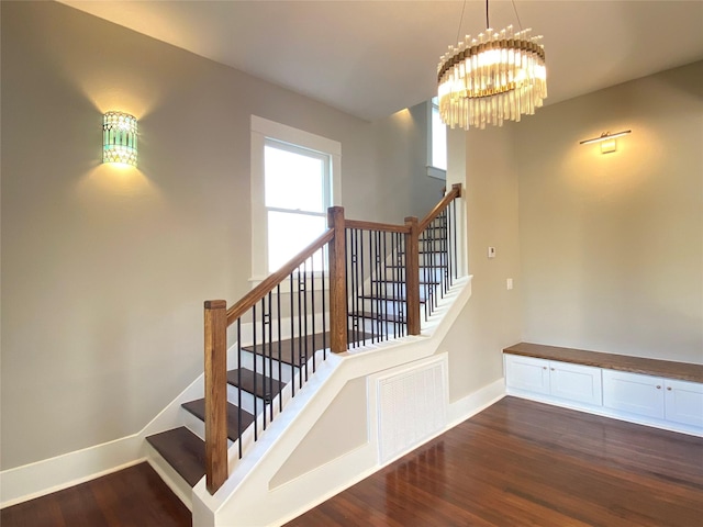 stairway with visible vents, baseboards, an inviting chandelier, and wood finished floors