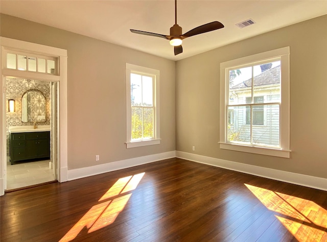 unfurnished room featuring a wealth of natural light, visible vents, and dark wood-type flooring