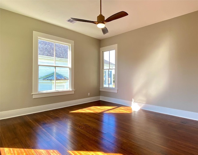 spare room featuring plenty of natural light, baseboards, and dark wood-style flooring