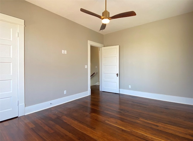 spare room with dark wood-style floors, a ceiling fan, and baseboards