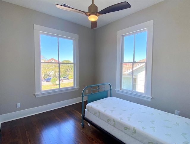 bedroom with baseboards, dark wood-type flooring, and a ceiling fan