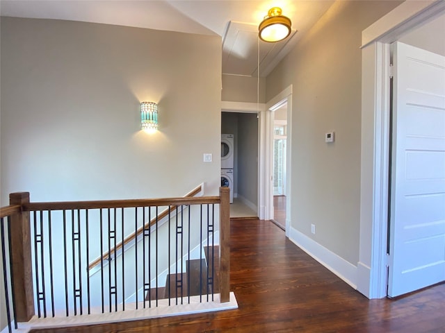 hall featuring stacked washer / dryer, baseboards, attic access, an upstairs landing, and wood finished floors