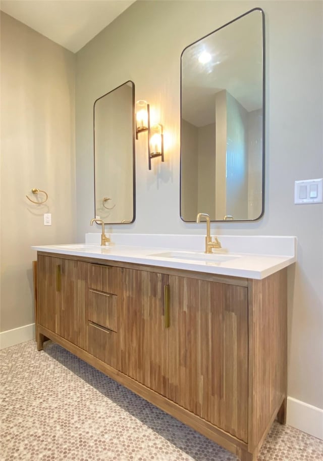 bathroom featuring a sink, baseboards, and double vanity