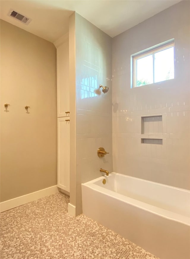 bathroom featuring visible vents, baseboards, and shower / washtub combination