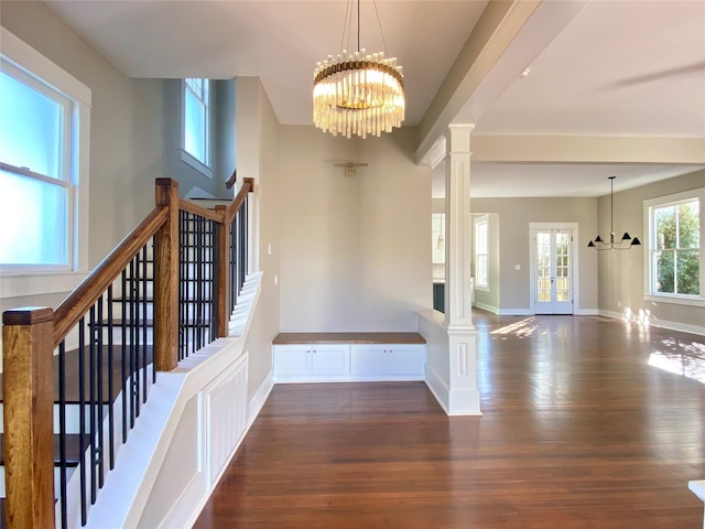 foyer with stairway, decorative columns, wood finished floors, and a chandelier