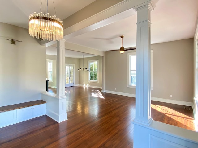 spare room with dark wood-style floors, ceiling fan with notable chandelier, baseboards, and decorative columns