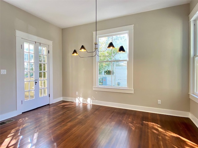 unfurnished dining area with visible vents, baseboards, a notable chandelier, and dark wood-style flooring