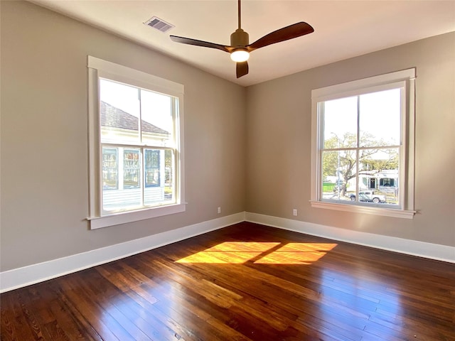 spare room with visible vents, baseboards, dark wood finished floors, and a ceiling fan