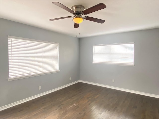 unfurnished room with baseboards, dark wood-style floors, and a ceiling fan