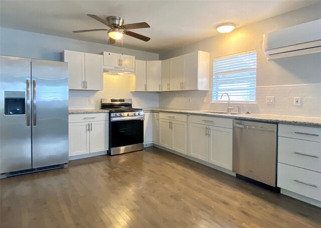 kitchen featuring a wall mounted air conditioner, a sink, under cabinet range hood, appliances with stainless steel finishes, and white cabinets