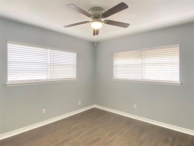 spare room with baseboards, dark wood finished floors, and a ceiling fan