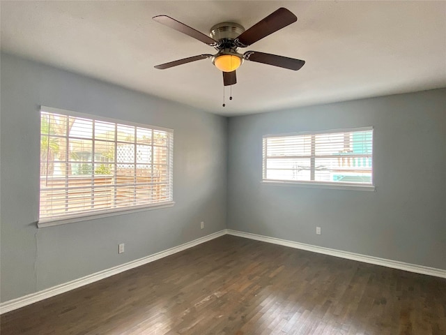 empty room with dark wood finished floors, plenty of natural light, and baseboards